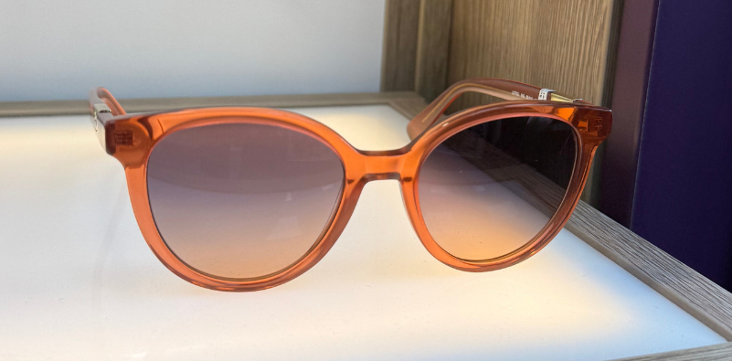 A pair of rounded, orange Longchamp sunglasses with a gradient purple lens tint