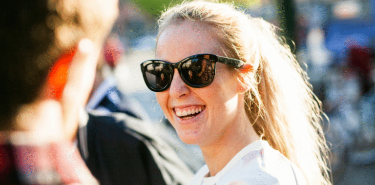 image of a young woman smiling, wearing sunglasses